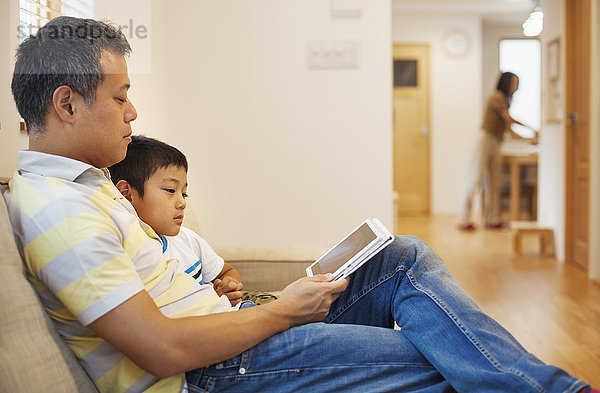 Familienhaus. Ein Mann und sein Sohn sitzen und lesen ein Buch.