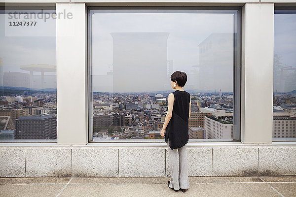 Eine Frau  die von einem hohen Aussichtspunkt aus über eine Stadt schaut.