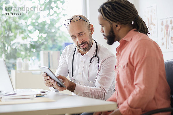 Arzt berät einen Patienten mit einem digitalen Tablet