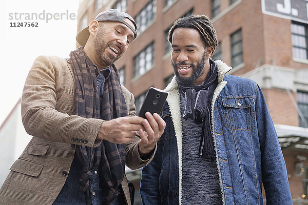 Lächelndes homosexuelles Paar  das ein Selfie mit einem Smartphone auf der Straße macht