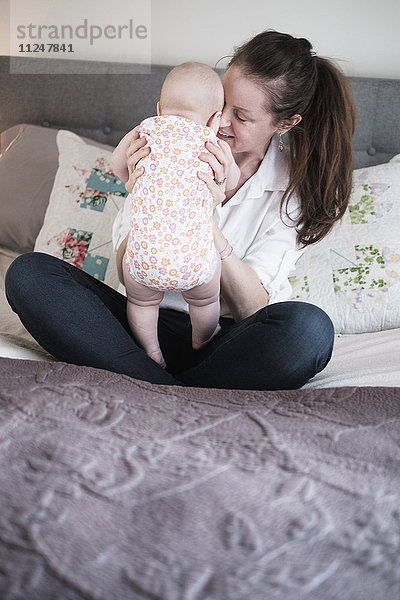 Mutter spielt mit ihrer kleinen Tochter (2-5 Monate) im Schlafzimmer