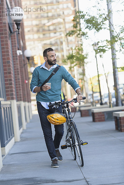 Mann zu Fuß mit Fahrrad in der Stadt