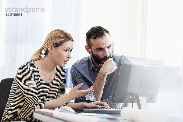 Mann und Frau schauen in einem Büro auf einen Computer