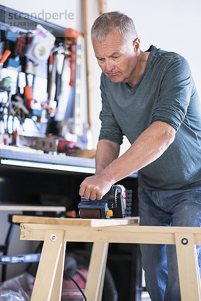Mann arbeitet mit Holz in der heimischen Werkstatt