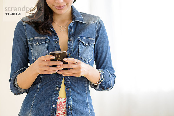 Mittelteil einer jungen Frau  die eine SMS schreibt