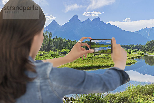 Junge Frau beim Fotografieren einer Bergkette