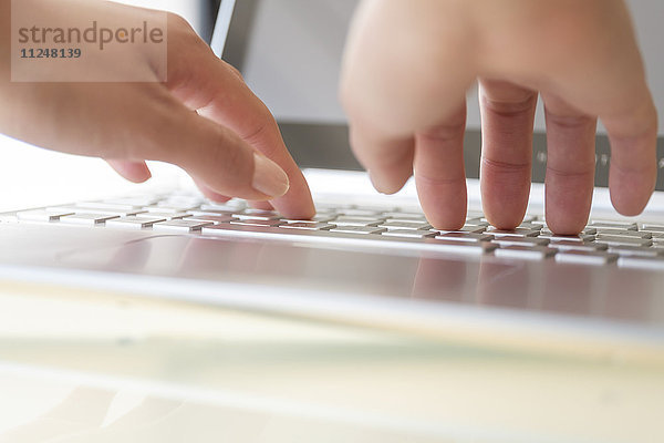 Hände beim Tippen auf der Laptop-Tastatur