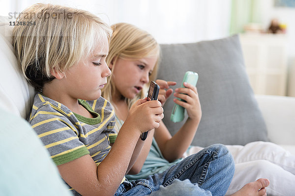 Junge (4-5) und Mädchen (6-7) spielen Spiele auf Smartphones