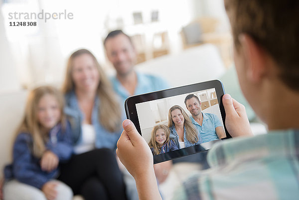 Junge (8-9) fotografiert Familie mit digitalem Tablet