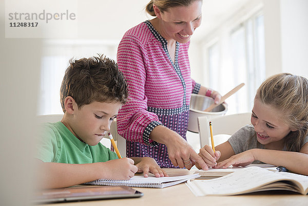 Mutter hilft Kindern (6-7  8-9) bei den Hausaufgaben