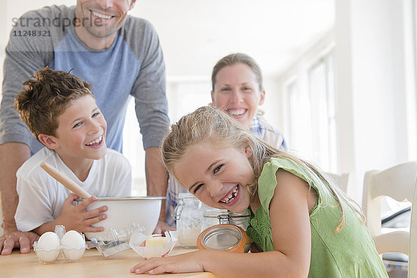 Familie mit zwei Kindern (6-7  8-9) bei der Essenszubereitung  lachend