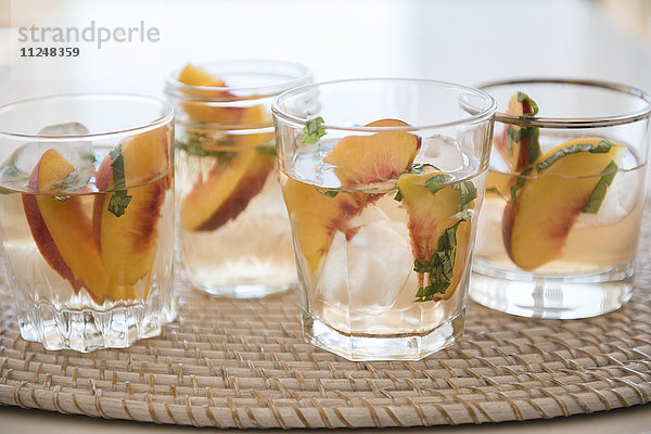 Cocktail mit Pfirsichspalten im Trinkglas