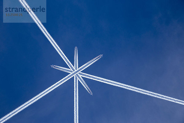 Gekreuzte Kondensstreifen von Flugzeugen am blauen Himmel