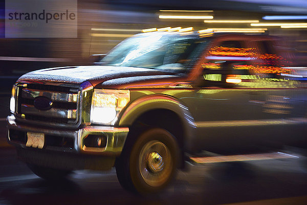 Lastwagen in beleuchteter Stadtstraße  in Bewegung bei Nacht