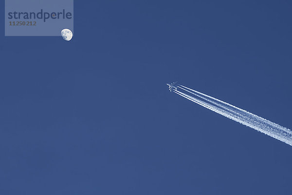 Flugzeug gegen blauen Himmel mit Mond