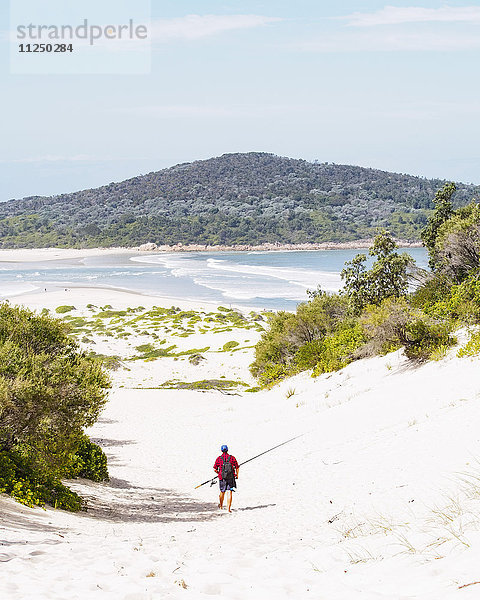 Mittlerer Erwachsener  der am Strand spazieren geht