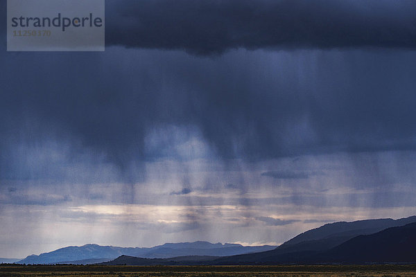 Gewitterwolken mit Regen über Bergen