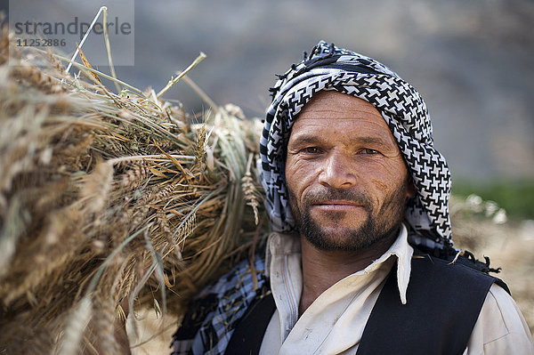 Ein afghanischer Mann aus dem Panjshir-Tal hält ein frisch geerntetes Weizenbündel  Afghanistan  Asien