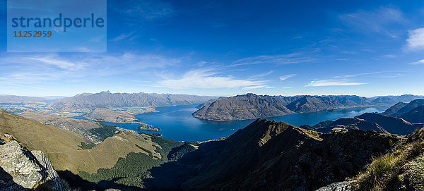 Steile  schroffe Berge  ein tiefblauer See und eine Bergstadt in Queenstown  Otago  Südinsel  Neuseeland  Pazifik