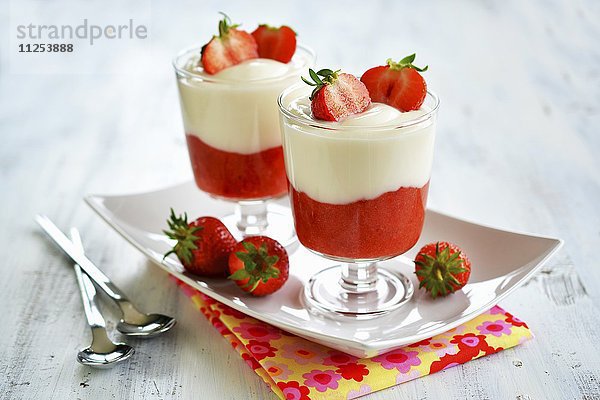 Dessert aus Erdbeermus und Joghurt in Gläschen auf Tablett  mit frischen Früchten dekoriert