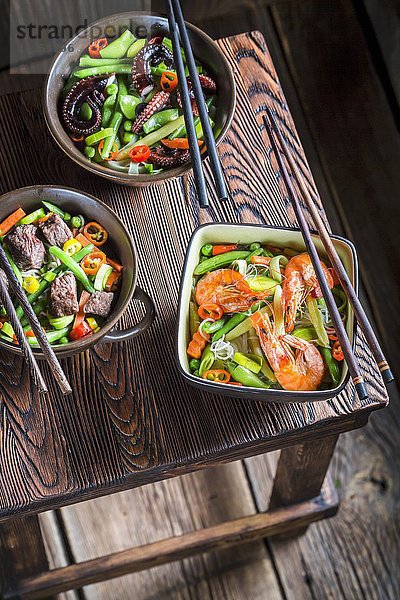 Drei Nudelgerichte mit Rindfleisch  Garnelen  Oktopus und Gemüse (Asien)