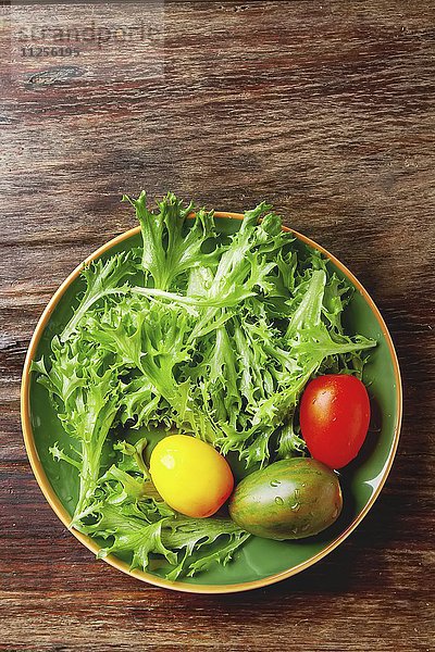 Frische grüne Salatblätter mit bunten Tomaten (Draufsicht)