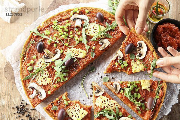 Vegane Pizza mit Ananas  Champignons und Oliven  teilweise in Stücke geschnitten