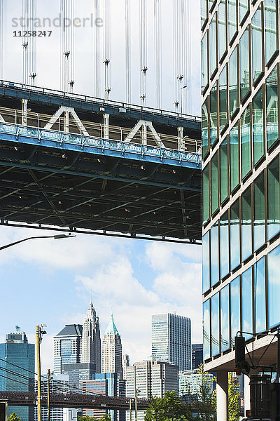 USA  New York State  New York City  Stadtpanorama mit einem Teil der Brooklyn Bridge und der Fassade eines Wolkenkratzers im Vordergrund