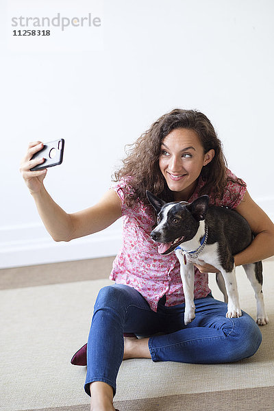 Frau hält Hund und macht Selfie