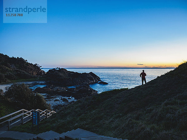 Australien  New South Wales  Port Macquarie  Silhouette eines Mannes mit Blick aufs Meer bei Sonnenaufgang