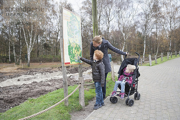 Mutter und Kinder (4-5  8-9) betrachten eine Karte im Park