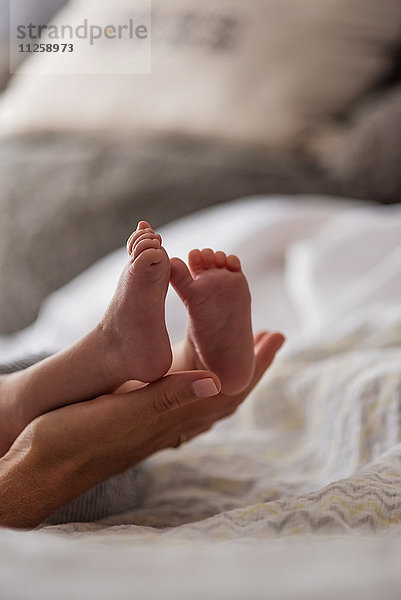 Mutter hält die Füße ihres Sohnes (0-1 Monate) im Schlafzimmer