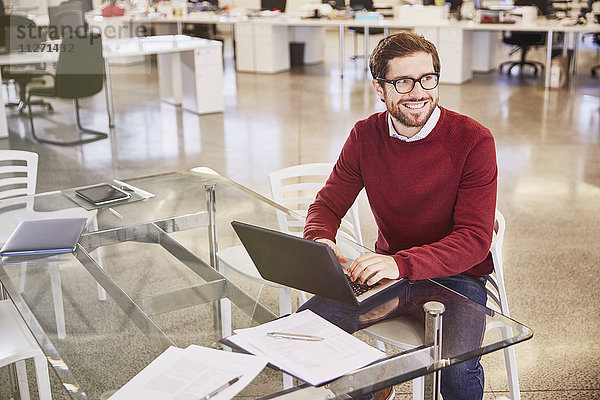 Lächelnder Geschäftsmann arbeitet am Laptop im Büro