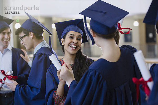 Fröhliche Studentinnen mit Mütze und Kittel und Diplomen beim Feiern