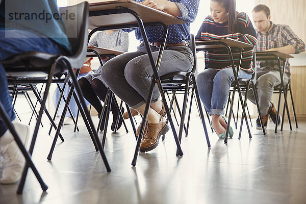 Studenten  die einen Test an einem Schreibtisch im Klassenzimmer ablegen.