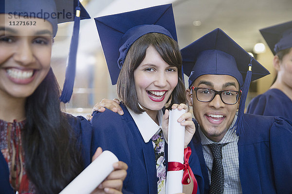 Porträt begeisterte Hochschulabsolventen in Mütze und Mantel posierend mit Diplom