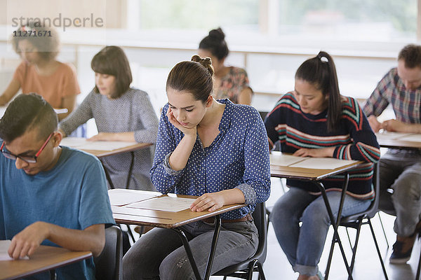 Studenten  die einen Test an einem Schreibtisch im Klassenzimmer ablegen.