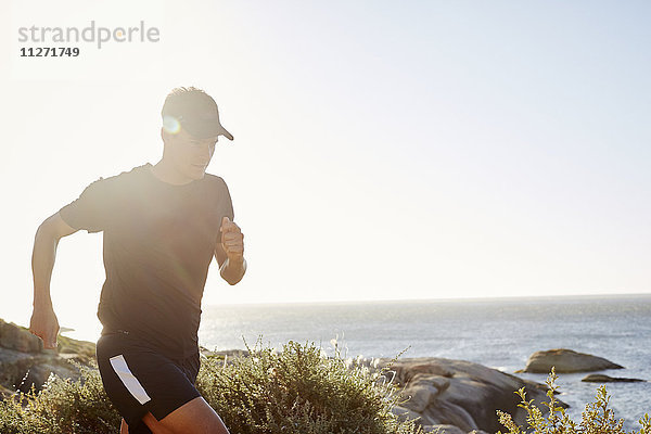 Männlicher Triathlet  der am Ozean entlang läuft