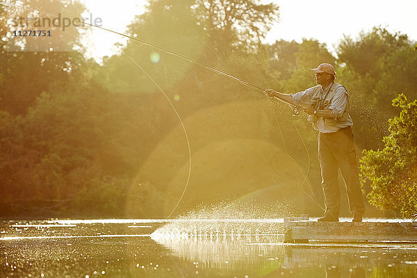 Senior Mann Fliegenfischen am sonnigen Sommersee