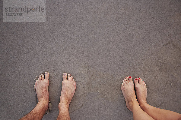 Persönliche Perspektive Barfuß-Paar im nassen Sand am Strand stehend