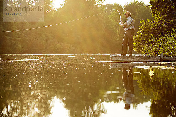 Senior Mann Fliegenfischen am Dock des Sommersees