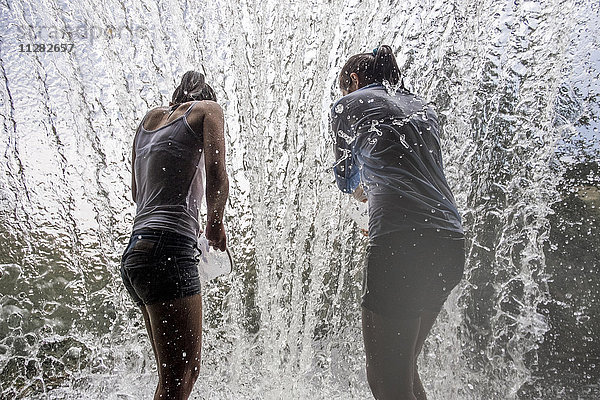 Kaukasische Mutter und Tochter stehen im Wasserfall