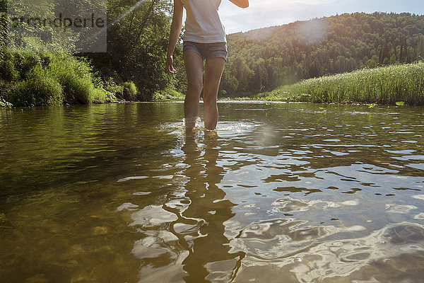 Kaukasische Frau watet im Fluss