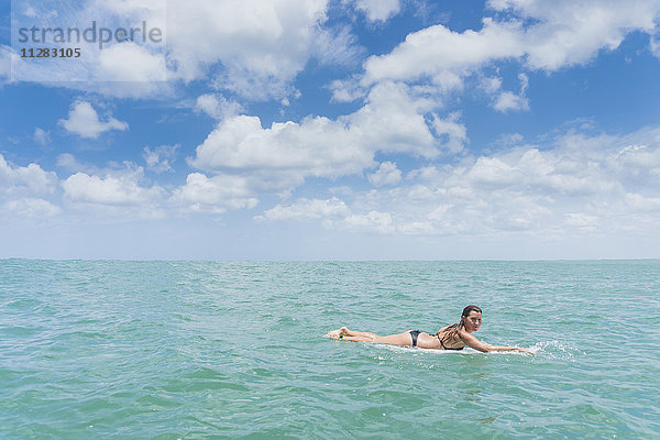 Kaukasische Frau paddelt auf einem Surfbrett im Meer