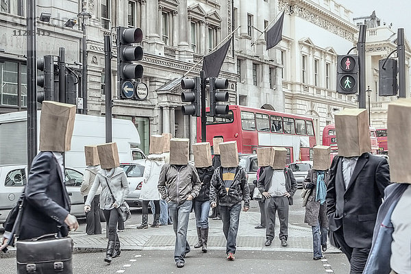 Anonyme Menschen mit Papiertüten auf dem Kopf in der Stadt