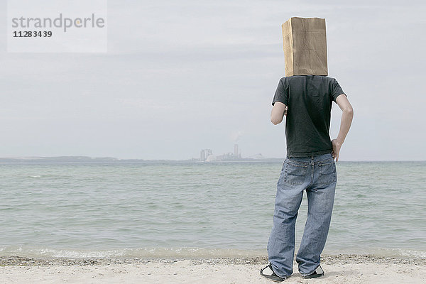 Mann mit Papiertüte auf dem Kopf beobachtet entfernte Skyline
