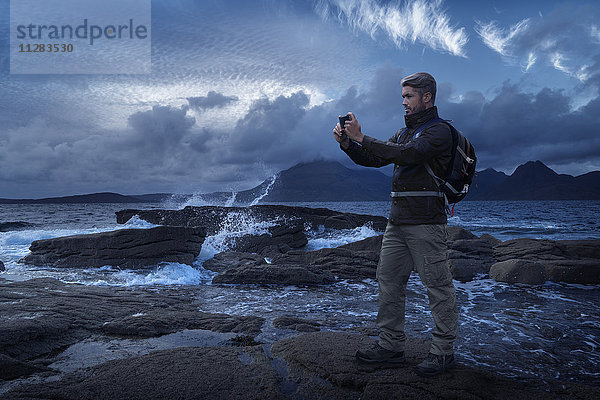 Kaukasischer Wanderer fotografiert das Meer mit seinem Handy