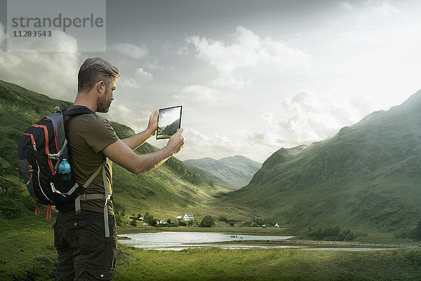 Kaukasischer Wanderer fotografiert Talsee mit digitalem Tablet
