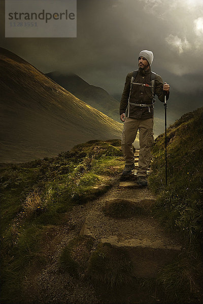 Kaukasischer Wanderer mit Wanderstock auf einem Bergpfad