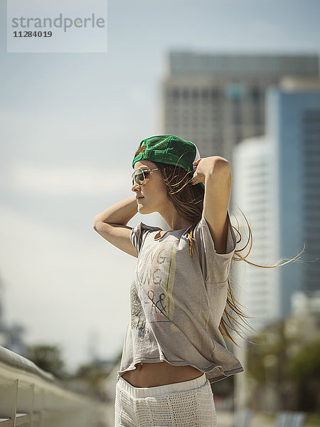 Kaukasische Frau mit Baseballmütze und Sonnenbrille im Wind